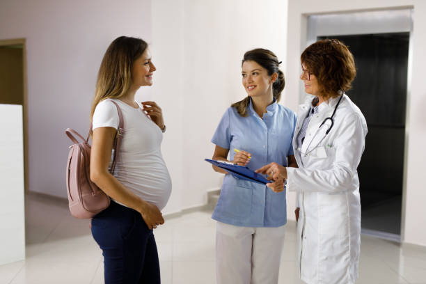 Confident female doctors consulting with a pregnant patient at a hospital